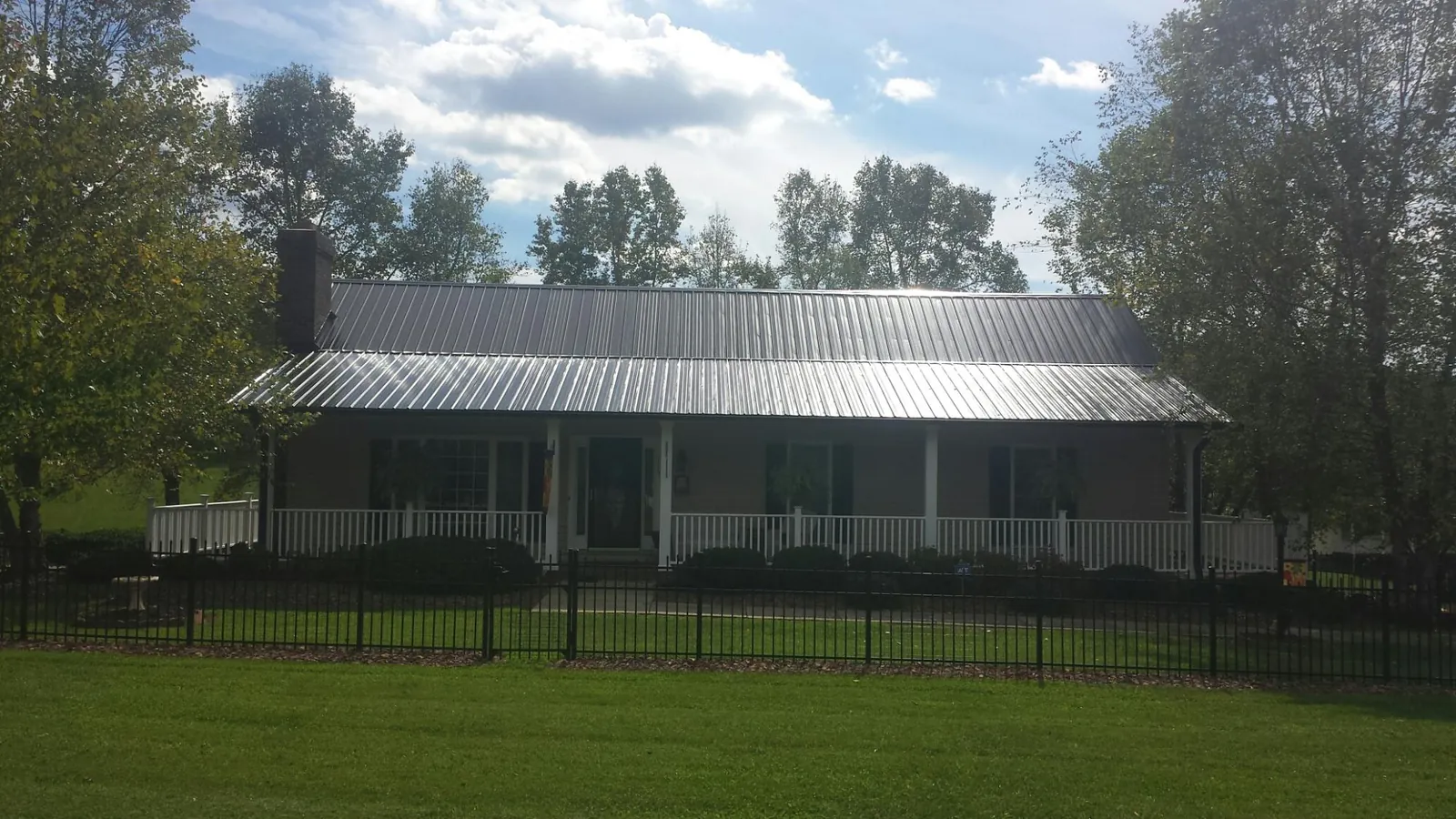 Gray metal roof on a brick ranch with a full width front porch — Gutter Guard Installation work by our crew in Curtis