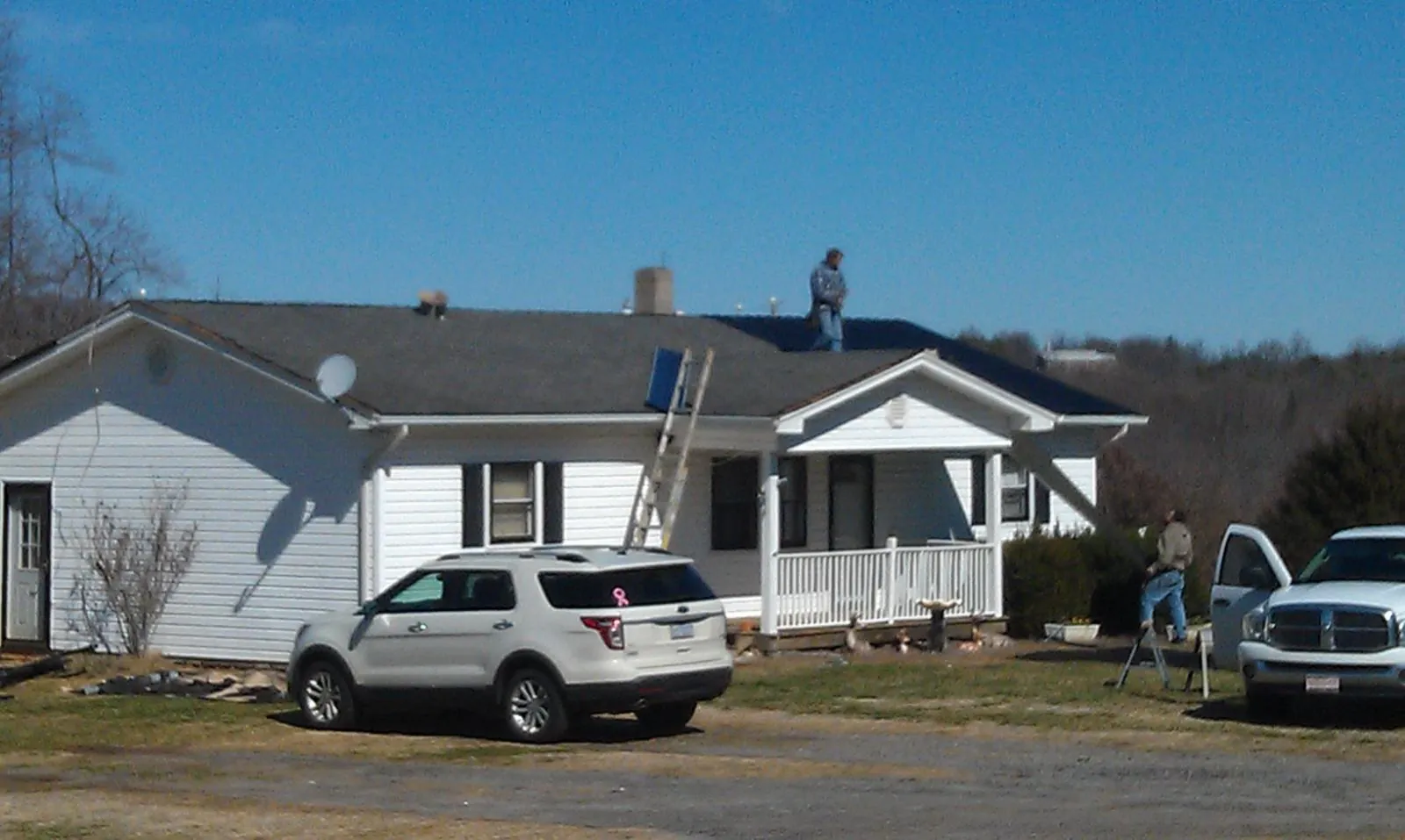 Roofers stripping shingles from a white ranch house roof in Curtis