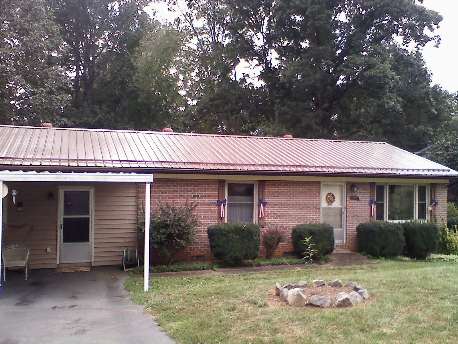 Bronze metal roof and carport on a brick ranch home — Roof Repair work by our crew in Curtis